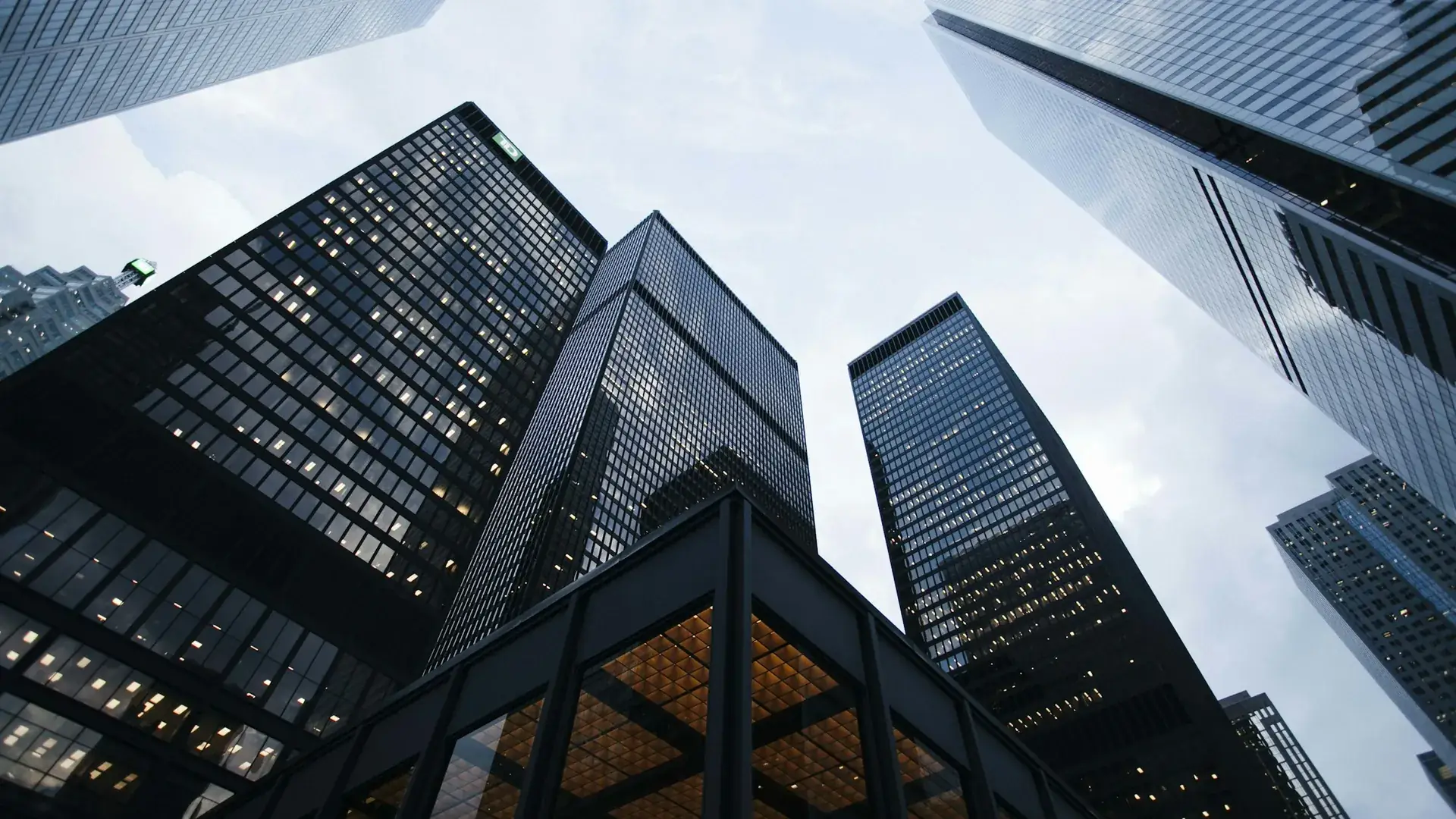 Glass office towers seen from street level against a pale sky